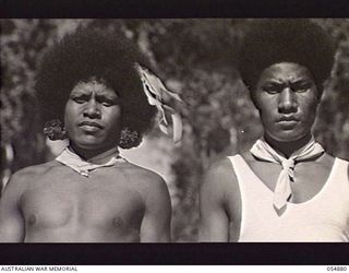 BULLDOG-WAU ROAD, NEW GUINEA, 1943-07-11. TWO NATIVE "BOSS BOYS", AVAU AITSI (LEFT) AND AITSI IRURU WHO ARE EMPLOYED TO DISCIPLINE NATIVE BEARERS AND ROAD WORKERS