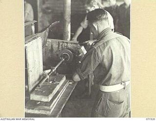 KOITAKI, PORT MORESBY AREA, PAPUA, NEW GUINEA. 1944-03-26. NX109687 SERGEANT E. GOODWIN AT THE LATHE, WITH NX154776 SERGEANT J. E. BREEZEL IN THE BACKGROUND, BOTH MEMBERS OF THE 113TH CONVALESCENT ..