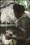 Man grinding shell money beads strung on special fiber