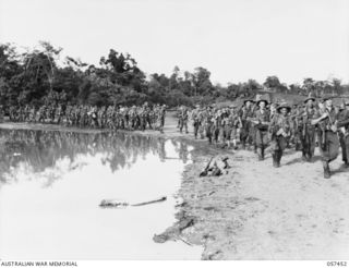 Troops of the Finschhafen Force marching to the beach for their embarkation on LSTs (Landing Ships, Tank).  Identified right to left: QX31360 Private (Pte) Stanley Wilson; unidentified; ..