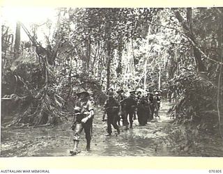 WEBER POINT, MALALAMAI, NEW GUINEA, 1944-02-09. MEMBERS OF "B" COMPANY, 30TH INFANTRY BATTALION, FOLLOWING A MUDDY TRACK BETWEEN WEBER POINT AND MALALAMAI. THEY HAVE BEEN ADVANCING FROM ROINJI (2) ..