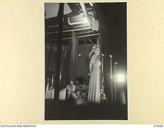 LAE, NEW GUINEA. 1944-07-24. CAROL LANDIS, AN AMERICAN MOTION PICTURE STAR, TELLS A STORY TO THE AUDIENCE DURING A CONCERT STAGED FOR THE TROOPS BY THE JACK BENNY SHOW