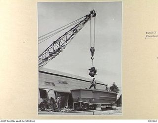 PURUATA ISLAND, SOUTH BOUGAINVILLE. 1945-05-29. A CRANE FITTING A NEW ENGINE INTO LANDING CRAFT PERSONNEL RAMP DURING MAINTENANCE BY 42 LANDING CRAFT COMPANY