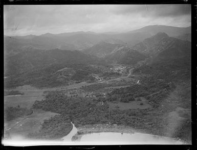 View of a coastal village with roads, forest and mountains beyond, Fiji