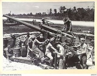 JACQUINOT BAY, NEW BRITAIN, 1945-08-31. A GUN CREW OF 141 HEAVY ANTI-AIRCRAFT BATTERY ROYAL AUSTRALIAN ARTILLERY WORKING ON A 3.7 INCH ANTI-AIRCRAFT GUN SITUATED IN A DEFENSIVE POSITION ON THE ..