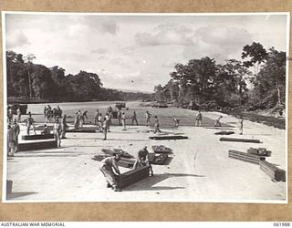 DREGER HARBOUR, NEW GUINEA. 1943-12-03. ENGINEERS OF THE 870TH UNITED STATES AVIATION ENGINEER BATTALION LAYING STEEL SECTIONS FOR A NEW LANDING STRIP WHICH WILL BE 6000 FEET LONG AND 110 FEET WIDE ..