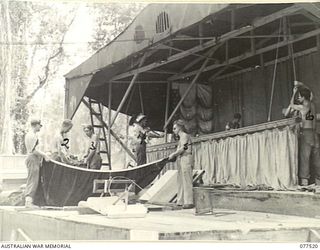 BOUGAINVILLE ISLAND. 1944-12-07. MEMBERS OF THE "TASMANIACS" - THE TASMANIA LINES OF COMMUNICATION CONCERT PARTY SETTING UP STAGE FOR THE EVENING PERFORMANCE. IDENTIFIED PERSONNEL ARE:- NX193842 ..