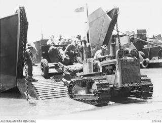 TSIMBA AREA, BOUGAINVILLE ISLAND. 1945-02-16. TROOPS OF NO. 12 FIELD BATTERY, 4TH FIELD REGIMENT, USING A SMALL TRACTOR TO LAND THEIR 25 POUNDER GUNS ON THE BEACH AT PUTO