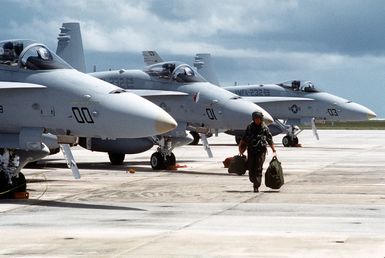 A pilot carries his gear across the flight line after disembarking from his aircraft, one of several Marine Fighter-Attack Squadron 232 (VMFA-232) F/A-18C Hornet aircraft lined up on the field during Operation Tandem Thrust '93