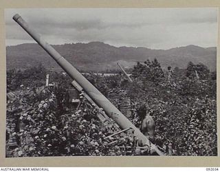 WEWAK POINT, NEW GUINEA, 1945-05-17. STAFF-SERGEANT A. ROSE, 2/2 FIELD REGIMENT, ROYAL AUSTRALIAN ARMY (1), EXAMINING A JAPANESE 75 MILLIMETRE ANTI-AIRCRAFT GUN ON THE NORTH EAST CORNER OF THE ..