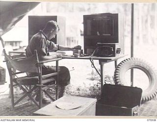 NORTH ALEXISHAFEN, NEW GUINEA. 1944-09-14. NX110632 CORPORAL R.D. KANE SPARE PARTS INTERPRETOR OF THE 133RD BRIGADE ORDNANCE FIELD PARK, WORKING IN THE CONTROL OFFICE CHECKING UNIT ORDERS FOR ..