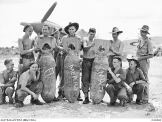 KIRIWINA, TROBRIAND ISLANDS, PAPUA. 1943-12-26. AN INFORMAL GROUP PORTRAIT OF ARMOURERS OF NO. 76 (KITTYHAWK) SQUADRON RAAF, WITH 500 LB BOMBS THAT WERE DROPPED FROM KITTYHAWK AIRCRAFT ON NEW ..