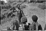 Distribution of wild pig meat: man with share of pork, pigs in background