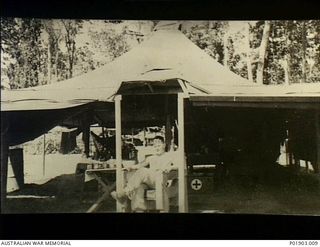 Torokina, Bougainville. 1944-11. Bill Blakely sitting in the "doorway" of the Regimental Aid Post now used by No. 1 and No. 3 Section, Detached, 2 Field Survey Company. This was formerly a US ..
