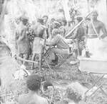 Native constables and others standing around a man sitting at a desk, New Guinea, c1924 to ?