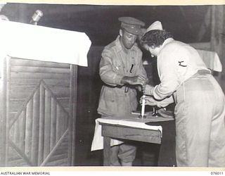 LAE, NEW GUINEA. 1944-09-18. LIGHTING CANDLES DURING THE JEWISH NEW YEAR SERVICE BEING CONDUCTED BY VX354 CHAPLAIN L.M. GOLDMAN AT HEADQUARTERS, NEW GUINEA FORCE. IDENTIFIED PERSONNEL IS:- VX39227 ..