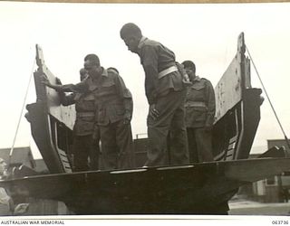 ALEXANDRIA, NSW. 1944-01-24. AUSTRALIAN AND NEW GUINEA ADMINISTRATION UNIT NATIVES INSPECTING A COMPLETED PLYWOOD LANDING BARGE AT SLAZENGER'S FACTORY