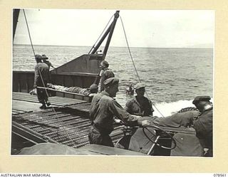 BOUGAINVILLE ISLAND, 1945-01-21. TROOPS OF THE 42ND INFANTRY BATTALION CARRYING BATTLE CASUALTIES ON TO A BARGE AT THE MAWARAKA BEACH- HEAD FOR TRANSPORT TO THE ADVANCED DRESSING STATION. ..
