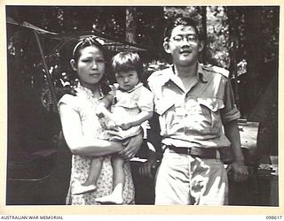 BITAPAKA, NEW GUINEA. 1945-11-04. MR B. CHAN WITH HIS WIFE AND FAMILY. HIS DAUGHTER STILL CARRIES THE SCAR OF BULLETS FROM A STRAFING CORSAIR AIRCRAFT. HE SPENT FOUR YEARS AT WESLEY COLLEGE, ..