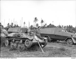 RAPOPO AIRSTRIP, NEW BRITAIN, 1945-09-19. A MEMBER OF 2/4 ARMOURED REGIMENT STANDING BESIDE A JAPANESE TYPE 97 TANKETTE. IN THE BACKGROUND ARE SEVERAL SURENDERED ARMOURED CARS. FOLLOWING THE ..