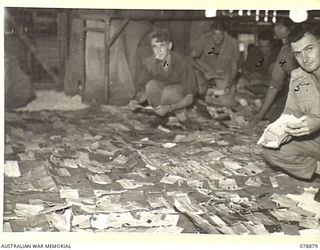 PALMALMAL PLANTATION, NEW BRITAIN. 1945-01-19. PERSONNEL OF FIELD POST OFFICE 0140 5TH BASE SUB AREA LAYING MAIL OUT TO DRY WHICH WAS SALVAGED AFTER BEING JETTISONED FROM A ROYAL AUSTRALIAN AIR ..