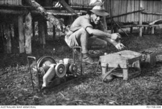 LUMI, NEW GUINEA. 1943-07. TX8688 SERGEANT LESLIE J. BAILLIE, WIRELESS OPERATOR, `LOCUST' PARTY, M SPECIAL UNIT, SERVICES RECONNAISSANCE DEPARTMENT, ALLIED INTELLIGENCE BUREAU, CHARGING A BATTERY ..