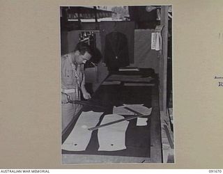 TOROKINA, BOUGAINVILLE. 1945-05-07. SERGEANT J.D. PALMER, TAILOR AT 4 SECTION OFFICERS' SHOP, ABOUT TO CUT OUT A UNIFORM