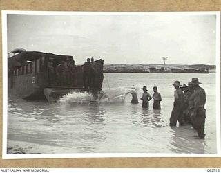 SIALUM, NEW GUINEA. 1944-01-05. PERSONNEL OF "D" COMPANY, 2/3RD AUSTRALIAN PIONEER BATTALION UNLOADING 44 GALLON DRUMS OF PETROL FROM AN LCM (LANDING CRAFT, MECHANISED) ON TO THE BEACH