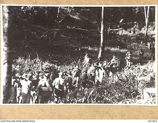 KOKODA TRAIL, NEW GUINEA. 1943-12-19. MEN OF THE 2/9TH AUSTRALIAN INFANTRY BATTALION AND NATIVE CARRIERS ACTING AS EXTRAS DURING THE FILMING OF "RATS OF TOBRUK" BY CHAUVEL'S PRODUCTIONS