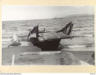 HANSA BAY, NEW GUINEA. 1944-06-17. THE MAST AND SUPERSTRUCTURE OF A JAPANESE FREIGHTER IN THE DISTANCE AND WRECKED JAPANESE BARGE IN THE FOREGROUND. ONE OF THE MANY SCENES OF DEVASTATION AFTER THE ..