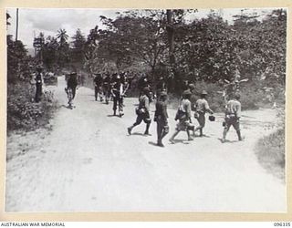 RABAUL, NEW BRITAIN, 1945-09-10. JAPANESE TROOPS CROSSING THE ROAD IN FRONT OF AUSTRALIAN SOLDIERS. TROOPS OF 4 INFANTRY BRIGADE OCCUPIED THE RABAUL AREA FOLLOWING THE SURRENDER OF THE JAPANESE