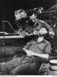 1943-07-14. NEW GUINEA. WAU-MUBO AREA. A DENTAL CLINIC POST IN A FORWARD AREA. CAPT. J. GRAY, OF OATLEY, N.S.W. GIVES TREATMENT TO PTE. G. VERITY, OF NARRABEEN, N.S.W. THIS DENTAL POST IS WITHIN ..