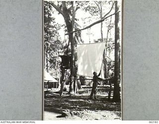 DUMPU, NEW GUINEA. 1943-12-10. MEMBERS OF THE 85TH AUSTRALIAN MOBILE CINEMA UNIT, AUSTRALIAN ARMY AMENITIES 7TH AUSTRALIAN DIVISION ERECTING THE SCREEN AND SOUND EQUIPMENT IN PREPARATION FOR THE ..