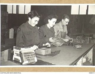 MEMBERS OF THE TROPIC PROOFING SECTION, 1ST BASE ORDNANCE DEPOT WRAPPING SPARE PARTS FOR SHIPMENT TO NEW GUINEA. LEFT TO RIGHT: VF511263 PRIVATE N. GRINTER, AUSTRALIAN WOMEN'S ARMY SERVICE (1); ..