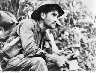 1943-08-03. NEW GUINEA. VX13245 PRIVATE. HERBERT GEORGE ESCREET, OF CARRAJUNG, VIC., RESTING DURING A HALT ON A TRACK IN THE MUBO AREA. (NEGATIVE BY G. SHORT)