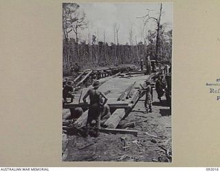 WARINGE RIVER, WEWAK AREA, NEW GUINEA, 1945-05-13. SAPPERS OF 8 PLATOON, 2/8 FIELD COMPANY, ROYAL AUSTRALIAN ENGINEERS, CONSTRUCTING A PERMANENT BRIDGE BESIDE A TEMPORARY PONTOON BRIDGE OF FOLDING ..