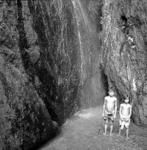 Children standing before waterfall