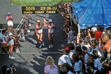 Onlookers applaud two contestants as they cross the finish line after completing the 26-mile marathon, part of the 1987 Ironman Competition