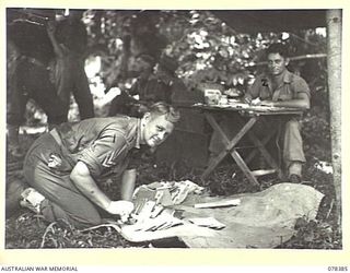 SAMPUN, NEW BRITAIN. 1945-01-16. VX131363 CORPORAL G.B. BELL (1); AND VX117507 PRIVATE R. MARTIN (2) OF THE 14/32ND INFANTRY BATTALION PREPARING OUTWARD MAIL FOR DESPATCH TO AUSTRALIA AT THE ..