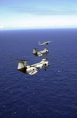 Two UH-46 Sea Knights and a UH-60 Black Hawk helicopter assigned to Andersen Air Force Base (AFB), Guam, fly over the Pacific Ocean