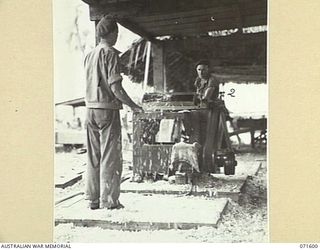 LABU POINT, LAE, NEW GUINEA. 1944-03-24. WX2469 CRAFTSMAN A. HUNT (LEFT), AND VX2469 CRAFTSMAN A. HUNT (1), AND VX80675 CRAFTSMAN H. L. GRANT (RIGHT), OPERATING A PLANING MACHINE IN THE CARPENTER'S ..