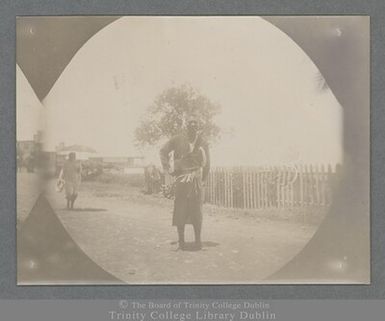 Photograph of a Samoan man using a tree branch and leaves as an umbrella in Apia, Samoa