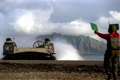 A member of the13th Marine Expeditionary Unit, Camp Pendleton, California guides the landing of Assault Unit 5 Landing Craft Air Cushion (LCAC) for the Non-combatant Evacuation Operation during exercise RIMPAC 98
