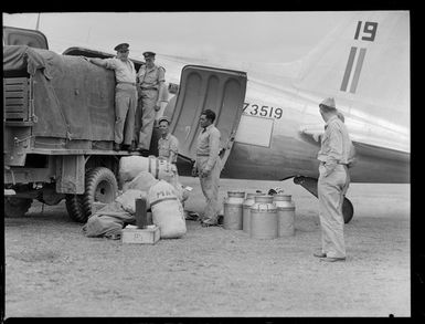 View of unidentified RNZAF personnel unloading mail from NZ3517 C47 transport plane on to a truck at [Fua'Amotu?] Airfield, Tonga