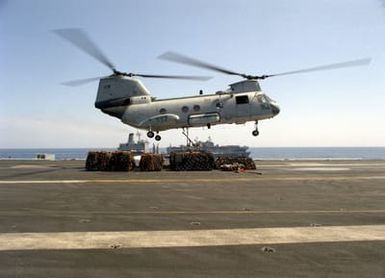 A flight deck crewman attaches a sling to the underside of an HH-46D Sea Knight from Helicopter Combat Support Squadron 6 (HC-6) during a vertical replenishment operation aboard the nuclear-powered aircraft carrier USS THEODORE ROOSEVELT (CVN-71). The fleet oiler USNS KANAWHA (T-AO-196) and the amphibious assault ship USS SAIPAN (LHA-2) are in the background. The Roosevelt Battle Group is assisting in enforcement of the no-fly zone over Bosnia-Herzegovina during Operation Deny Flight