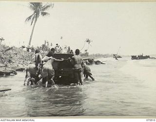 HANSA BAY, NEW GUINEA. 1944-09-06. NEW GUINEA NATIVES PUSHING A JEEP OF THE 7TH INFANTRY BRIGADE OUT OF A SOFT SECTION OF THE SAND ON THE BEACH. IN THE JEEP ARE: VX89946 GUNNER H.J. SWIFT, 2/14TH ..