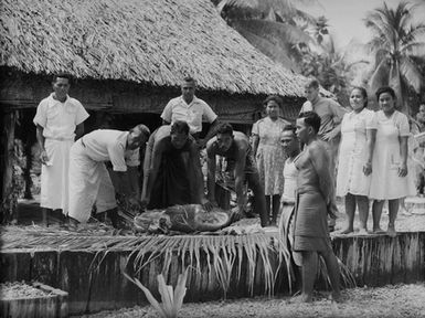 [Men displaying a cooked pig]