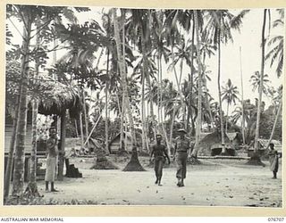 JACQUINOT BAY, NEW BRITAIN. 1944-11-06. VX47614 MAJOR B.G. DAWSON, 1ST NEW GUINEA INFANTRY BATTALION, WITH A NATIVE GUARD INSPECTING POMIO VILLAGE IN PREPARATION FOR ESTABLISHING A PERMANENT ..