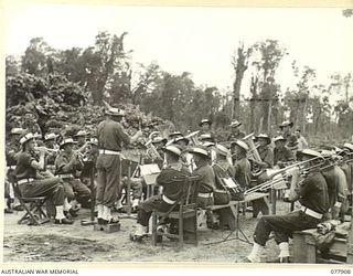 TOROKINA, BOUGAINVILLE ISLAND. 1945-01-01. THE BAND OF THE 29TH INFANTRY BRIGADE PROVIDING MUSICAL ENTERTAINMENT BETWEEN EVENTS AT THE ATHLETIC MEETING ORGANISED BY HEADQUARTERS, 3RD DIVISION