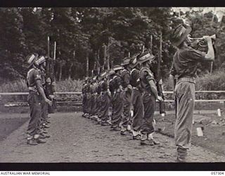 SOPUTA, NEW GUINEA. 1943-09-29. BUGLER SOUNDING THE LAST POST WHILE THE FIRING PARTY "PRESENT ARMS" AT THE FUNERAL OF BRIGADIER R. B. SUTHERLAND. SHOWN IS SERGEANT JOHNS (2)